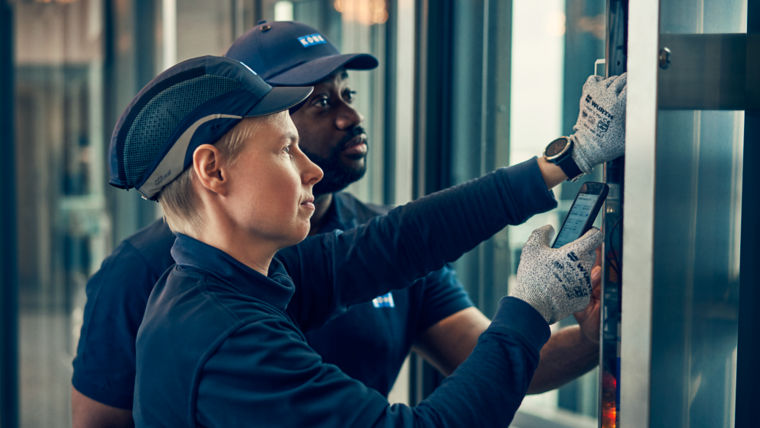 Two KONE maintenance technicians at work using mobile.