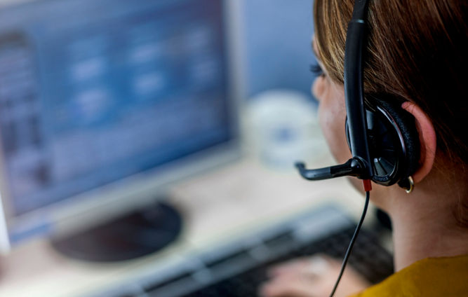 Mujer con auriculares frente a computadora - Servicio al cliente
