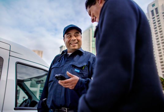 KONE maintenance service worker conversing with client outside.