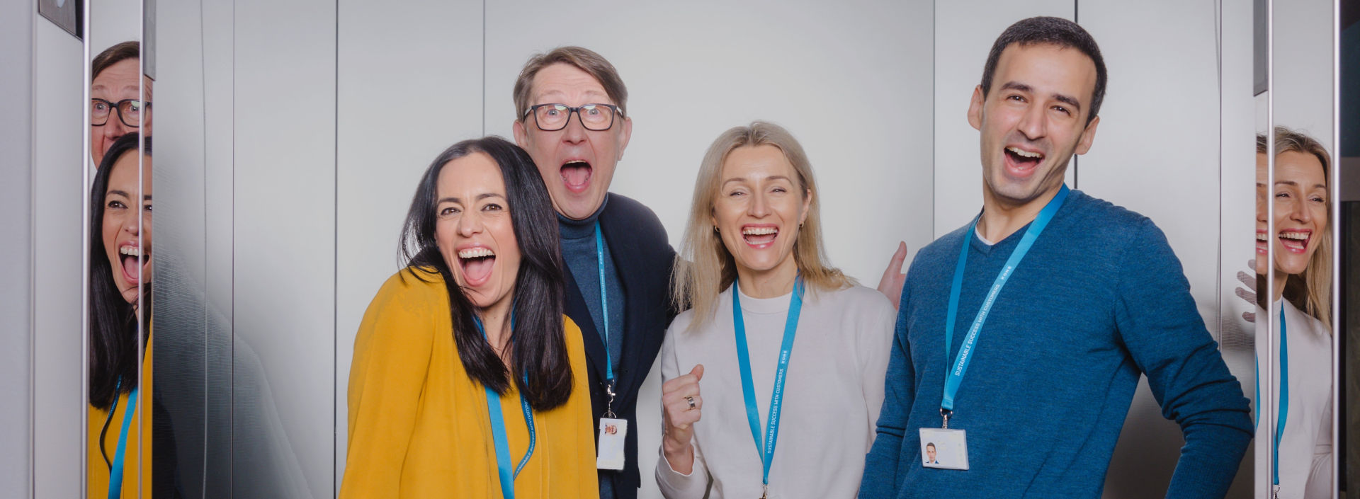 KONE employees laugh and pose in an elevator.