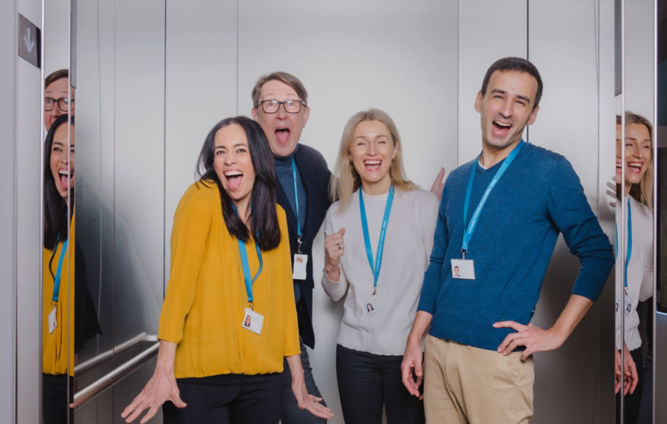 Empleados de KONE ríen y posan en un elevador