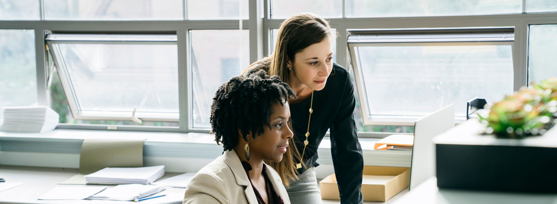 Two women looking at computer screen in an office - KONE