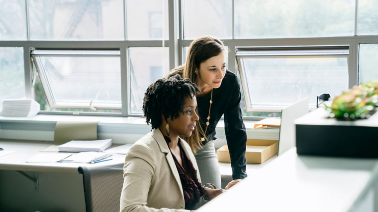 Two women looking at computer screen in an office - KONE