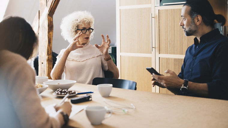 People conversing in a meeting room around a table - KONE Maintenance