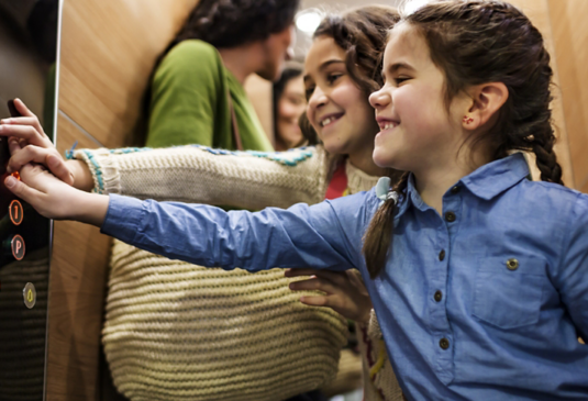 Kids selecting the floor by pushing elevator buttons - KONE Modernization