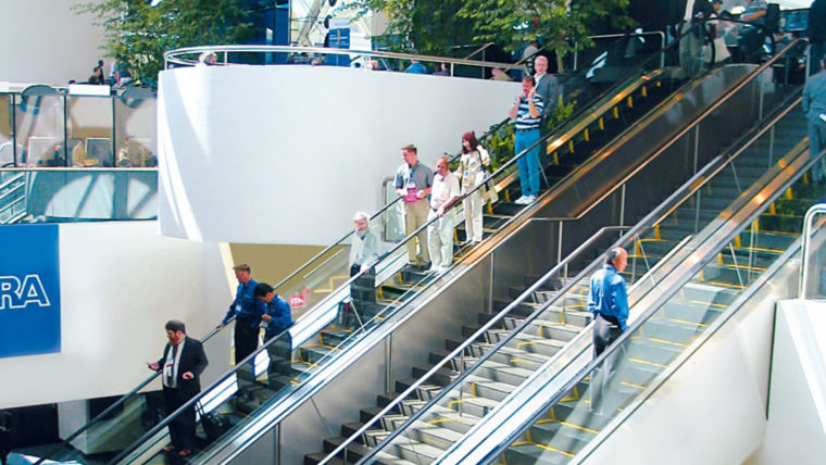 Gente dentro de un centro comercial subiendo y bajando escaleras eléctricas - KONE