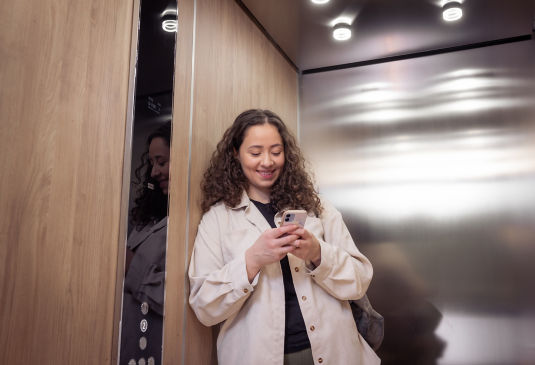 Woman phone elavator KONE MonoSpace DX 550