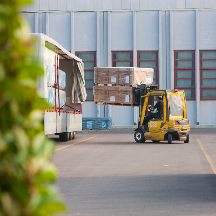 Forklift loading a truck outside a factory.