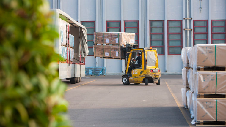 Forklift loading a truck outside a factory.