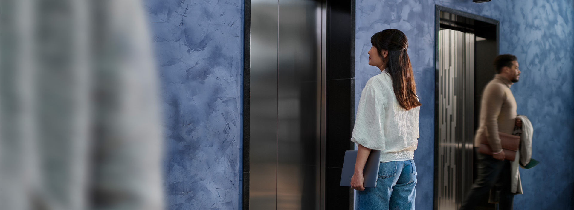 Mujer viendo hacia la puerta de un elevador - Moderniza tu elevador con KONE