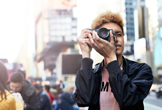 Un homme avec un appareil photo prenant des photos dans une rue animée.