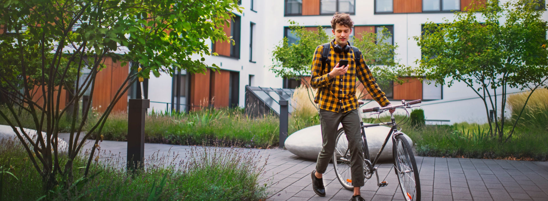 Cyclist walking his bike in a green residential area.