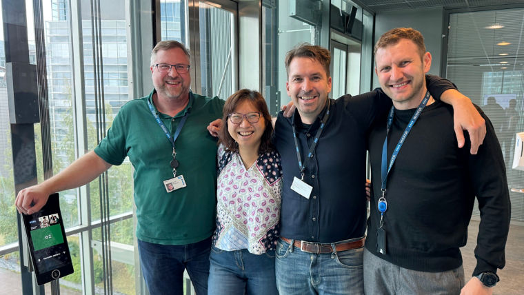 KONE team standing arms around shoulders in elevator lobby.