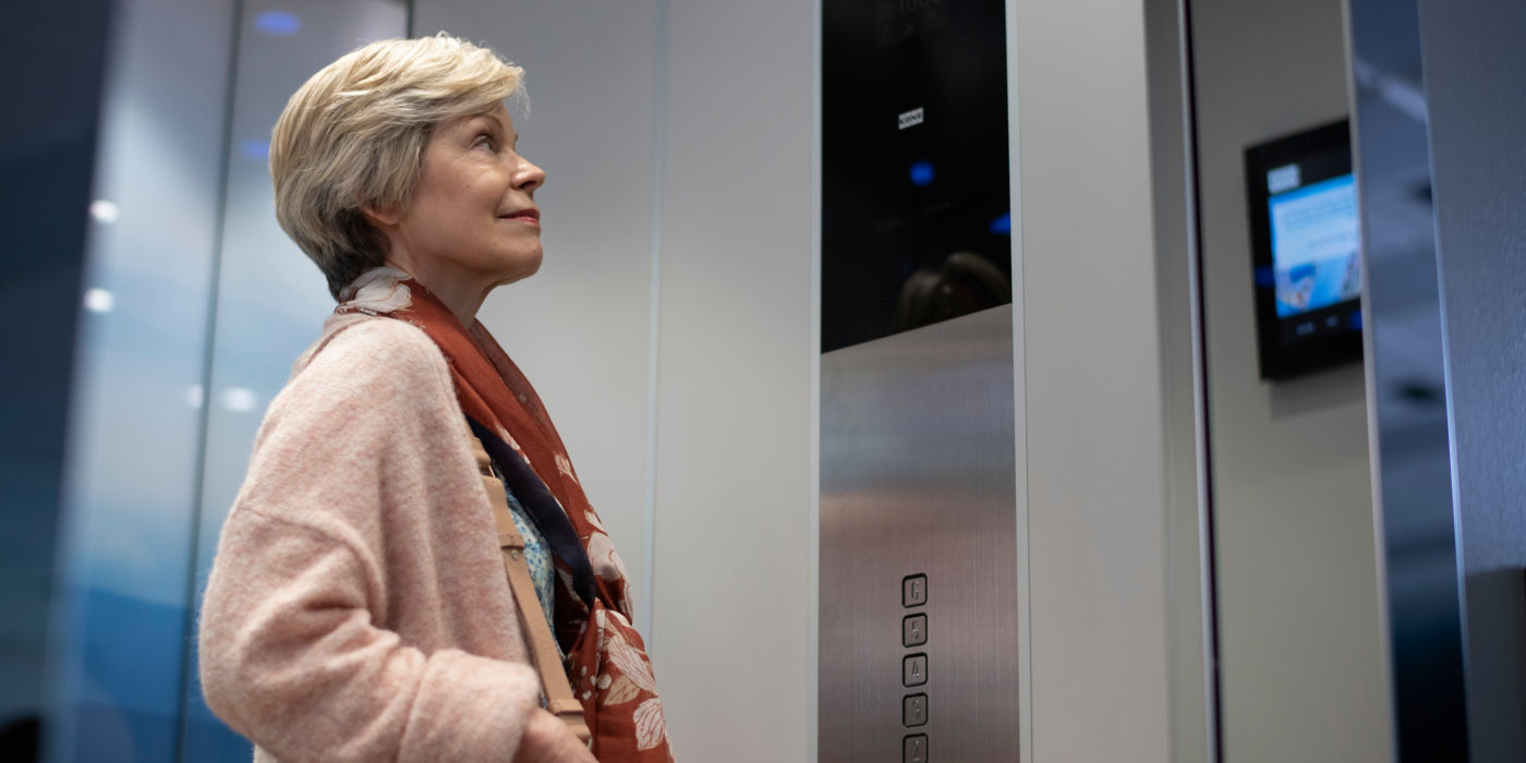 Elderly woman looking at information screen in an elevator.
