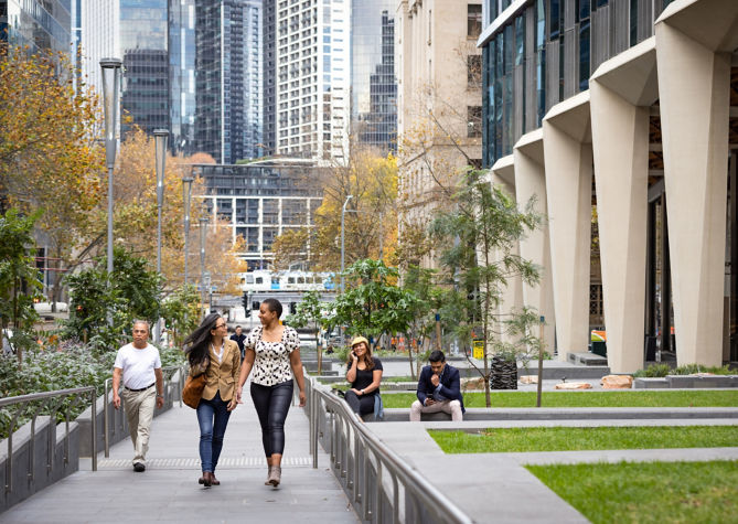 mujeres caminando por una calle urbana con vegetación