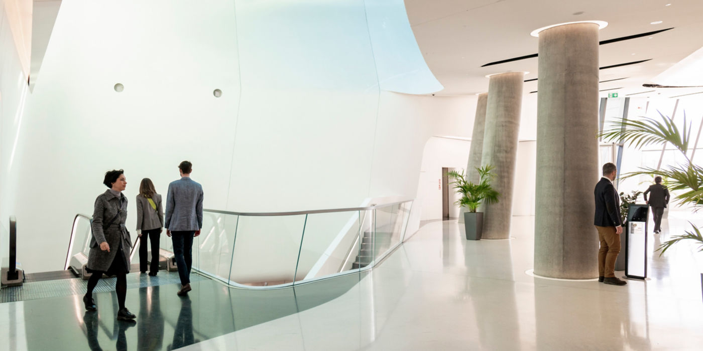 People in modern office using escalator and destination control.