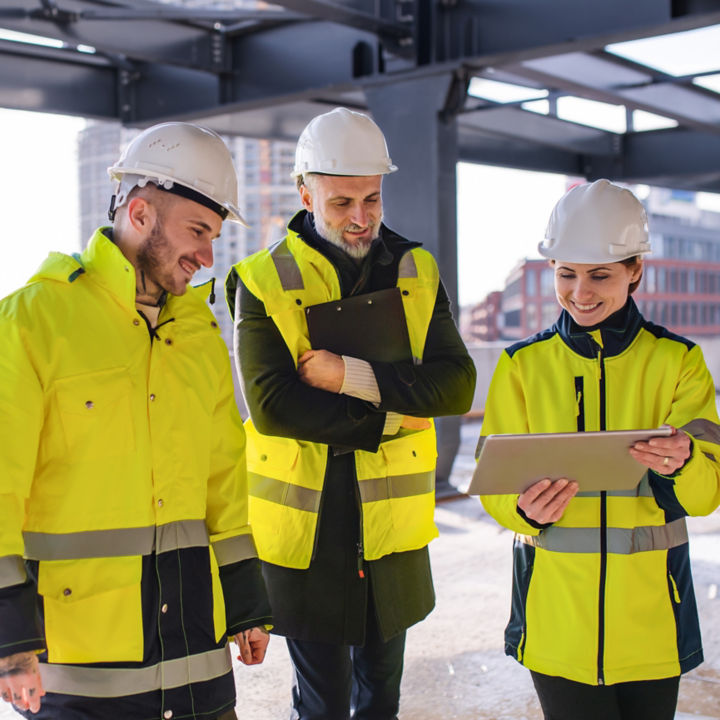 Group of engineers standing on construction site using tablet.