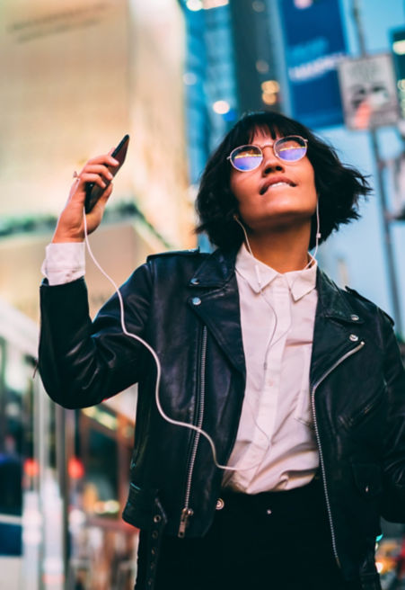 jeune femme écoutant de la musique dans une rue urbain animée - KONE Ascenseur connecté.