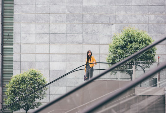 Mujer bajando escaleras ele´ctricas en el exterior