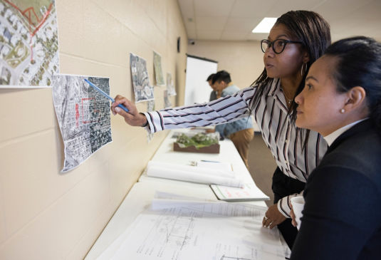 deux femmes discutant devant des plans.