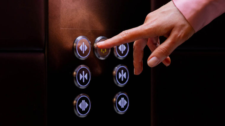 Mujer presionando el botón del elevador – elevadores KONE