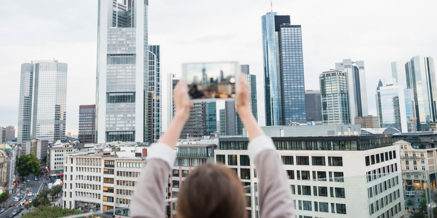 Woman taking a picture of the city skyline with a tablet.