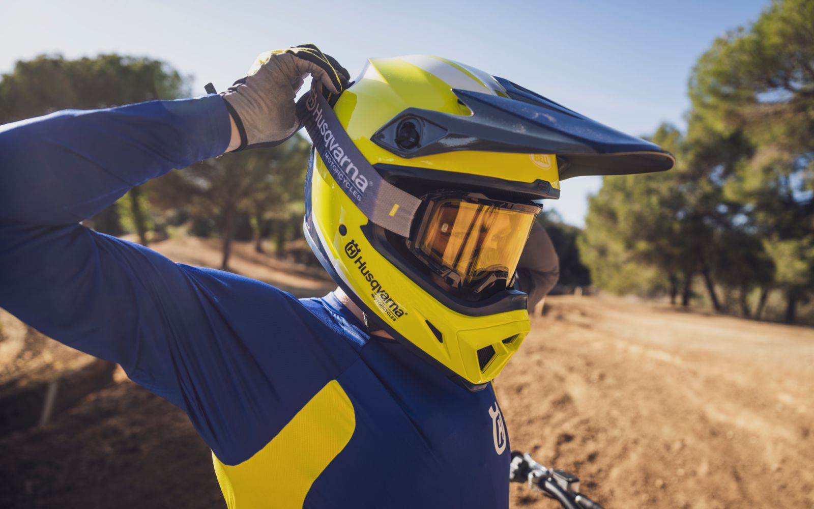 A motocross rider slightly jumping over a small hill on the motocross track