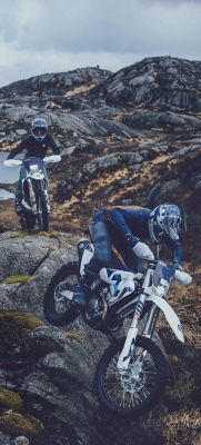An enduro rider is riding through the forest uphill