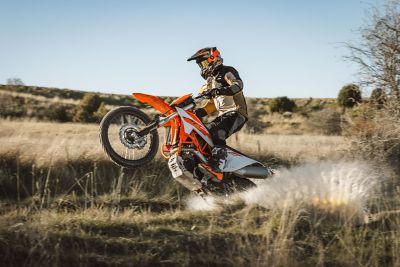 Rider drives an KTM Electric Bike along a rugged, rocky trail surrounded by natural terrain.