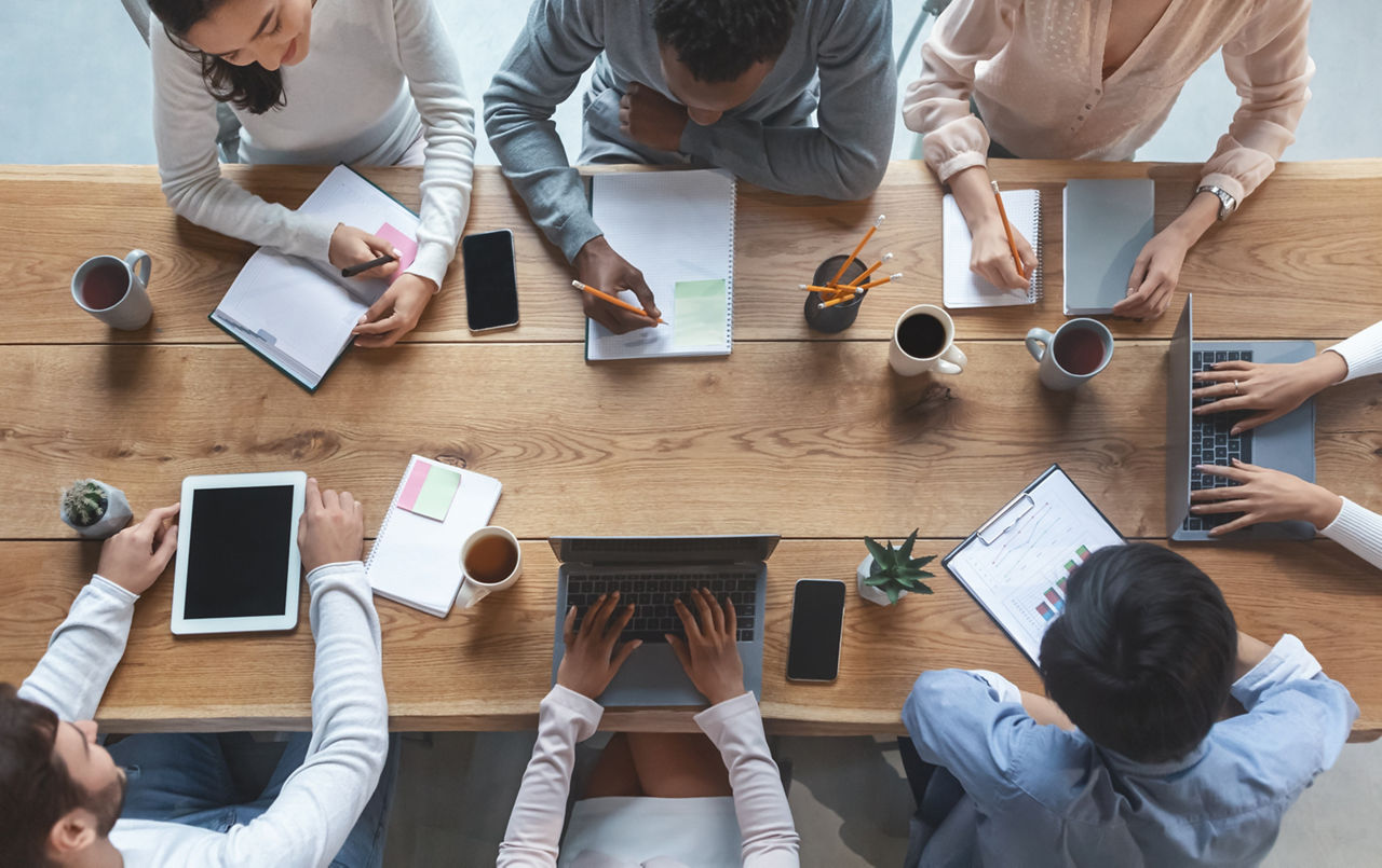 Office lifestyle. International young business team having morning briefing at office, top view