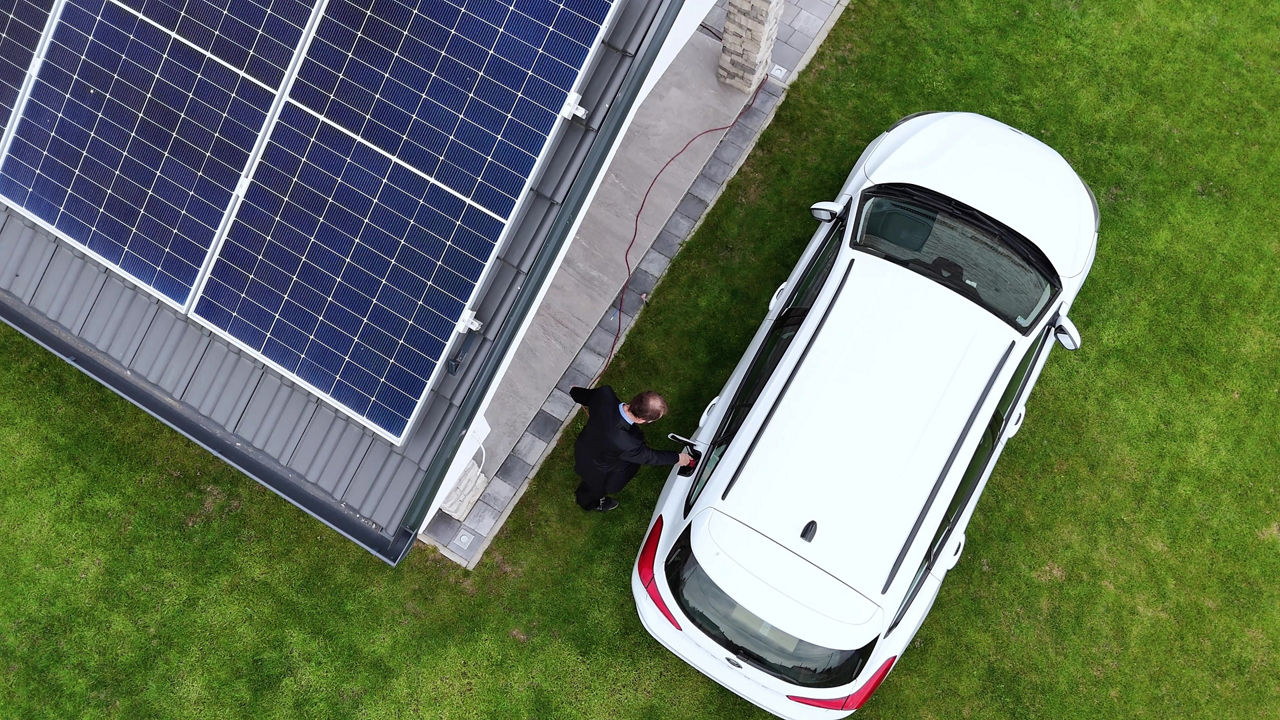 Electric car being charged at home with solar panel installed on house rooftop