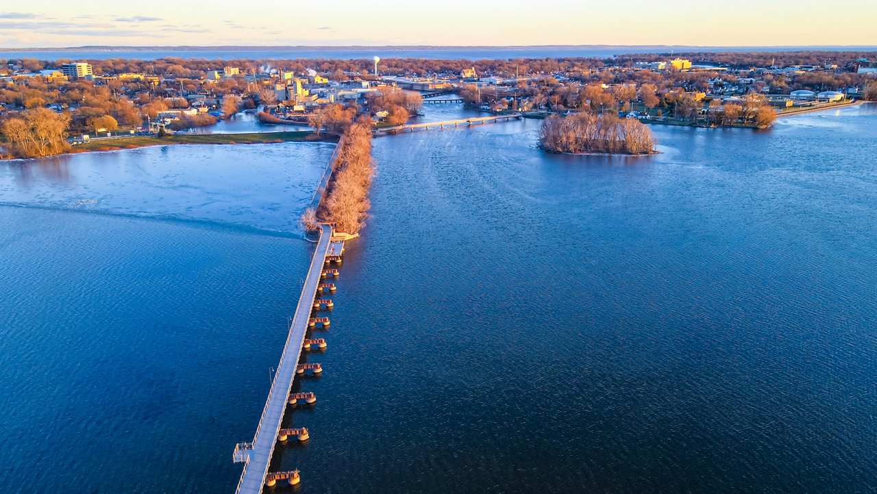 Vue aérienne d’automne du sentier en pont traversant le lac vers l’autre ville de l’autre côté au crépuscule 