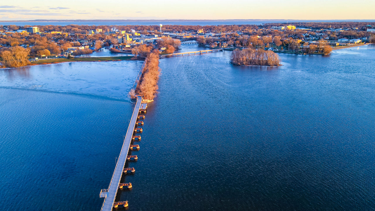 Autumn aerial view of the trestle trail heading across the lake to the other city on the other side at dusk 