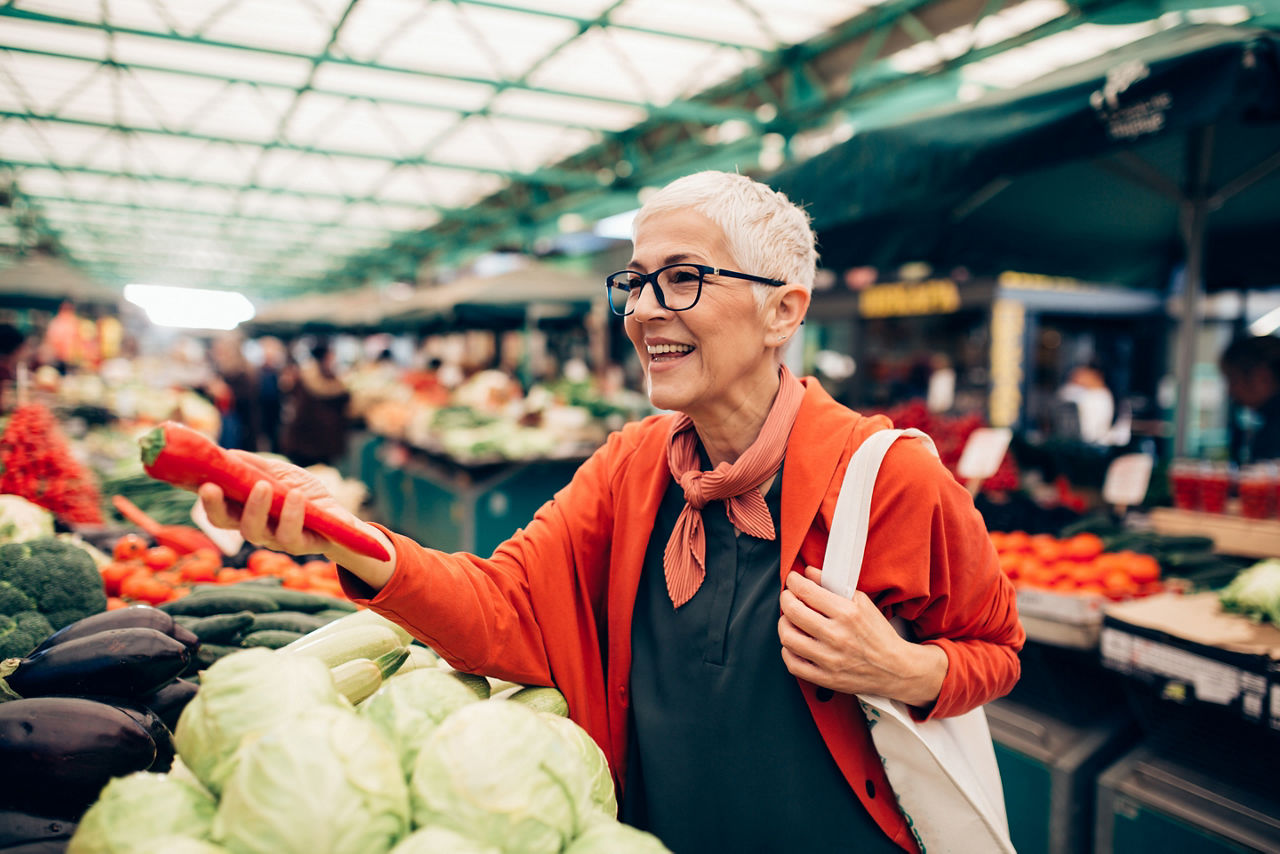 Person choosing fresh fruit and vegetables at an indoor market.