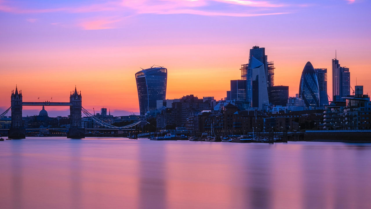 London skyline at sunset with the River Thames, Tower Bridge and modern skyscrapers.