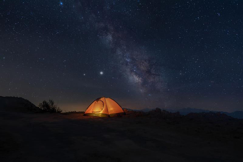 glowing tent in front of stary sky