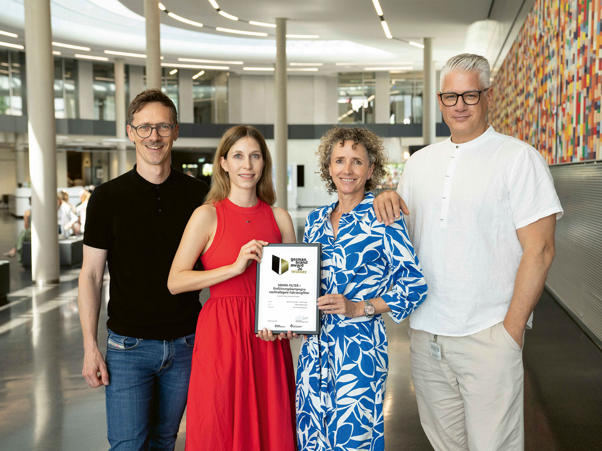 Four persons standing next to each other and holding the German Brand Award 2026 in their hands