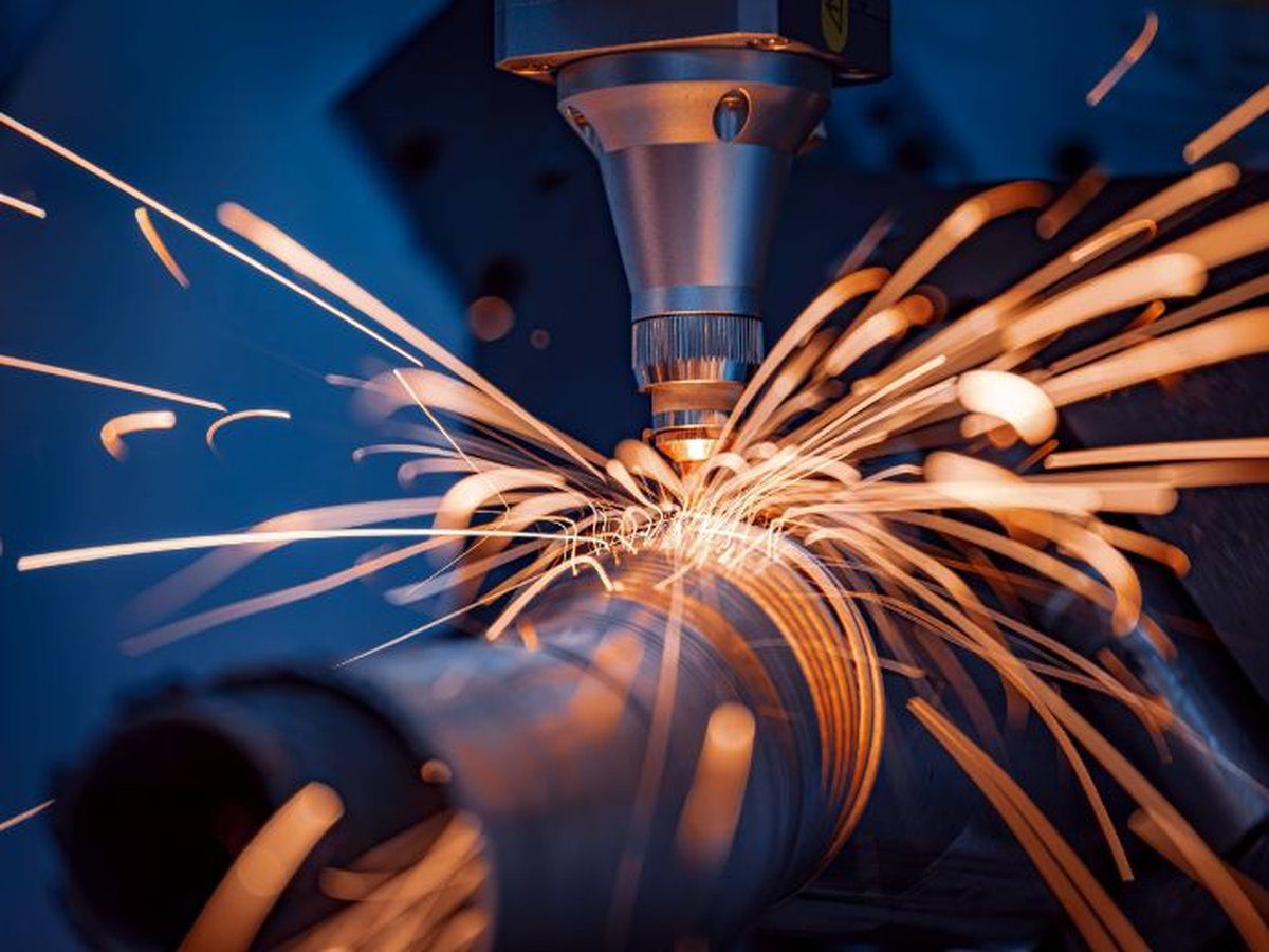 Close-up of a CNC machine cutting metal with sparks flying, highlighting the importance of air filtration in production halls to manage particulate matter and fumes.