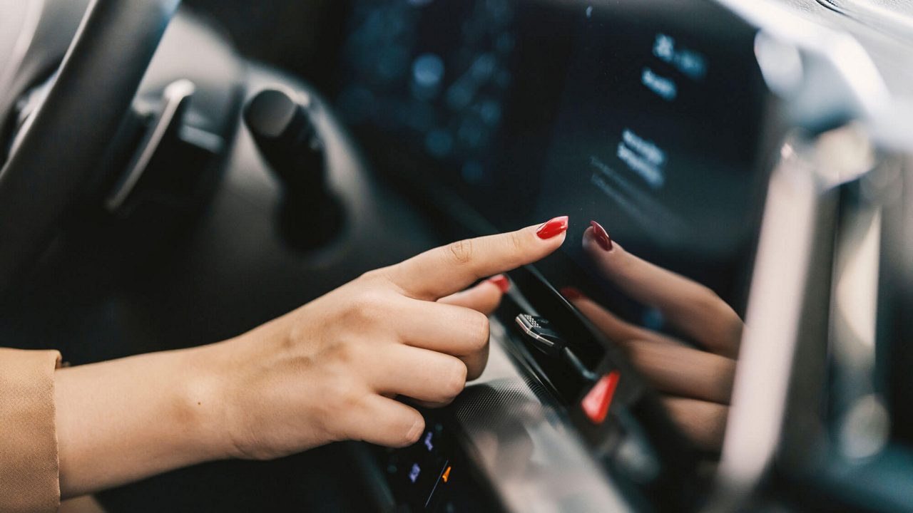 Eine Frau berührt den Touchscreen in einem Auto.