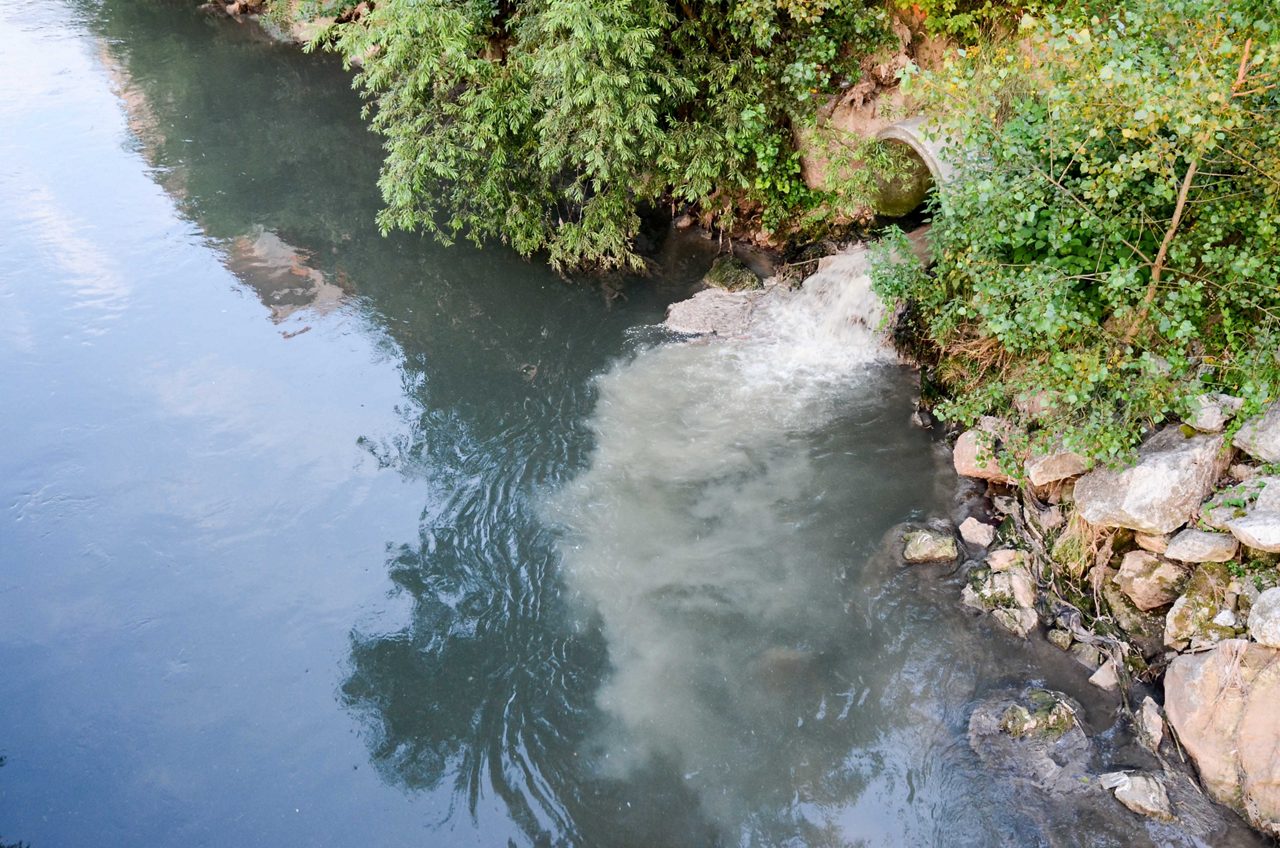 Sewage drains into the river. Environmental pollution. Ecological catastrophe and disaster. Water contamination. Sewage discharge to clear water. Wastewater. 