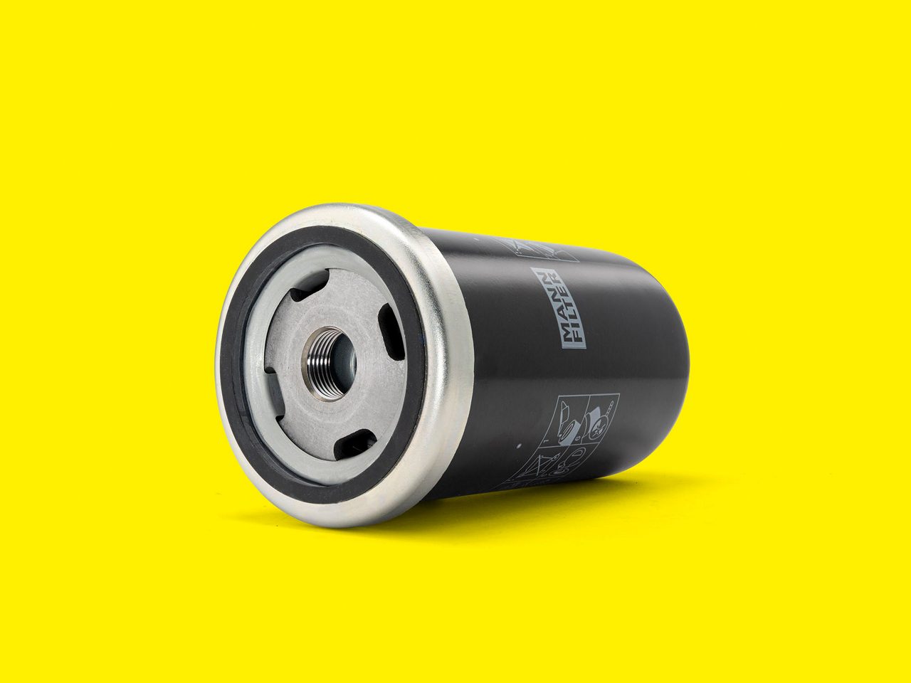 A black and silver MANN-FILTER hydraulic filter for industrial engines shown on a yellow background
