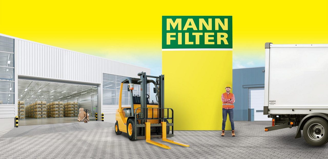 A yellow forklift in a warehouse with a MANN-FILTER box near material handling equipment