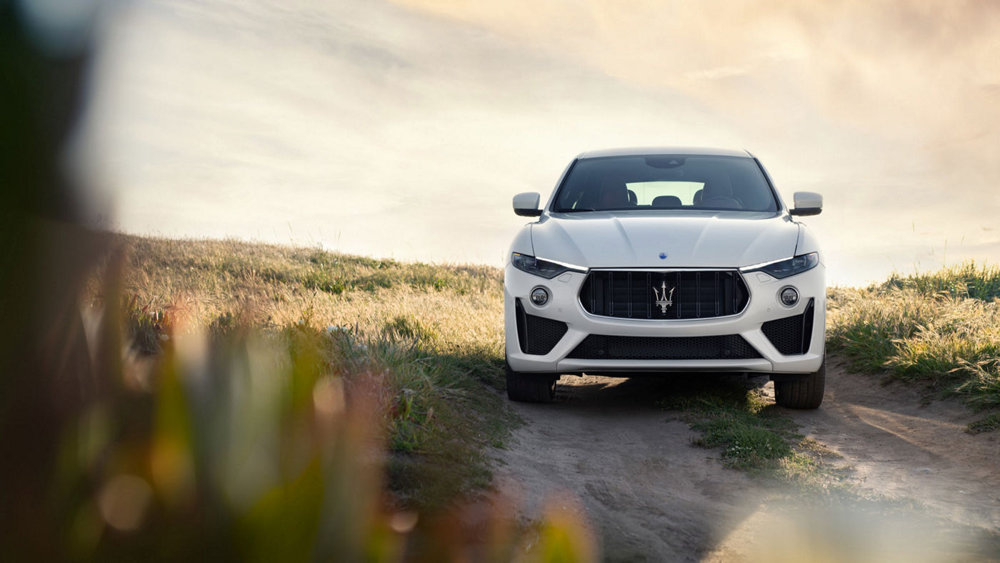 Maserati Levante on a gravel road - green field on the background