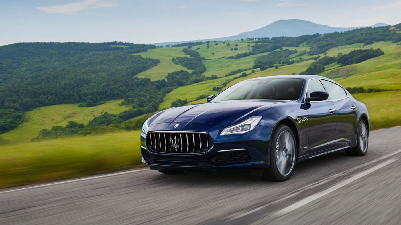 Maserati Quattroporte on the road - green hills on the background