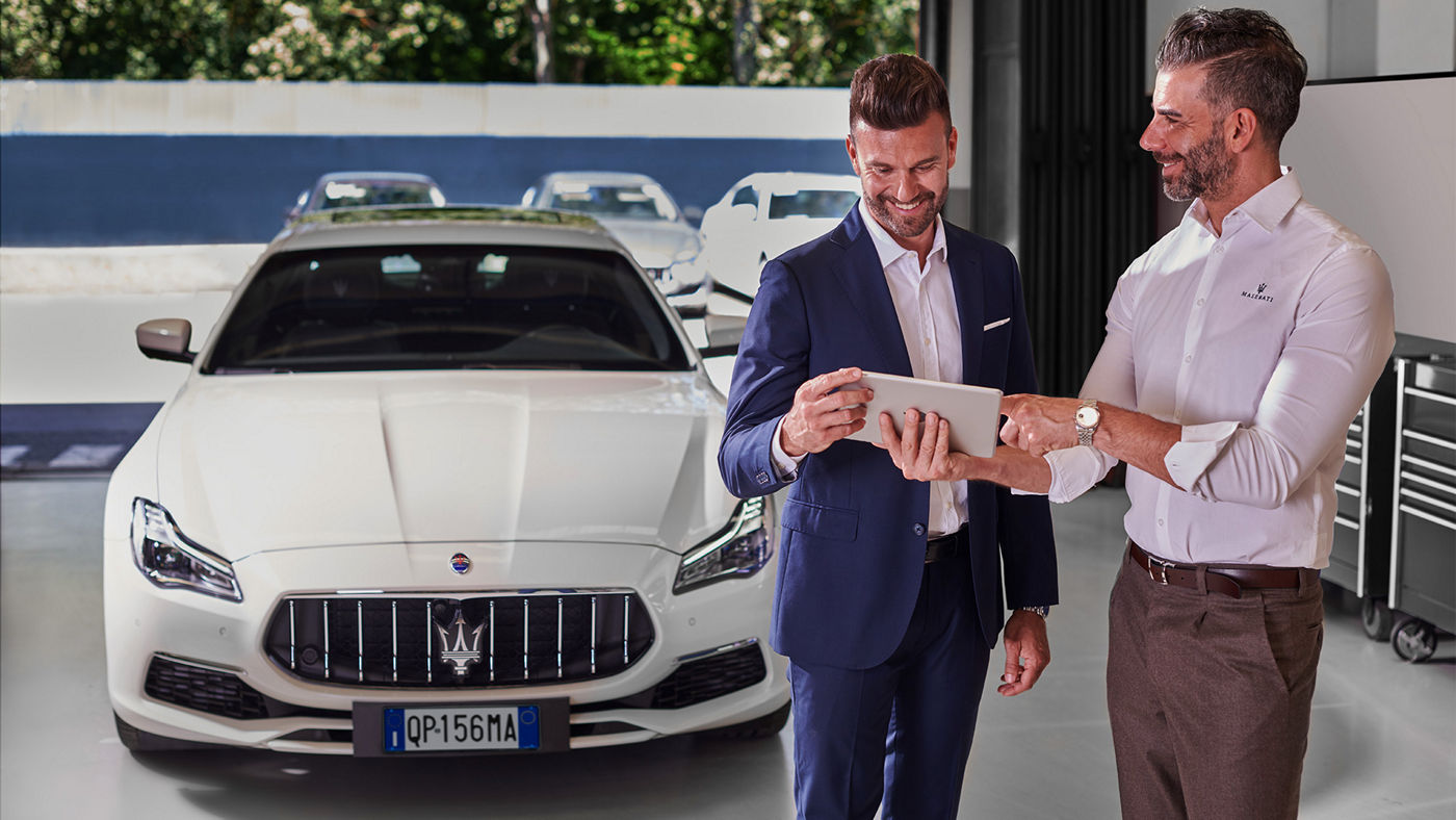 Dos señores en un concesionario delante de un vehículo Maserati