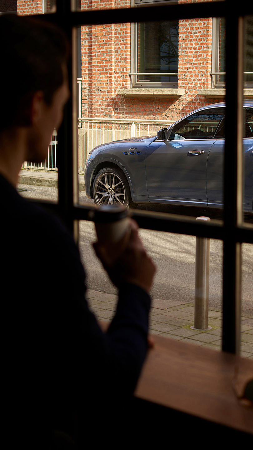 Hombre que mira por la ventana el SUV Maserati Levante GT