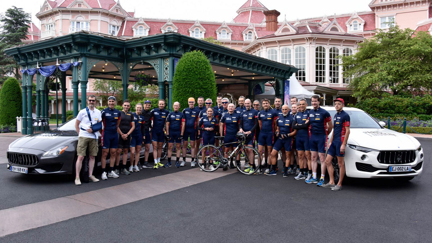 Ciclistas delante de modelos Maserati en frente del hotel Disneyland