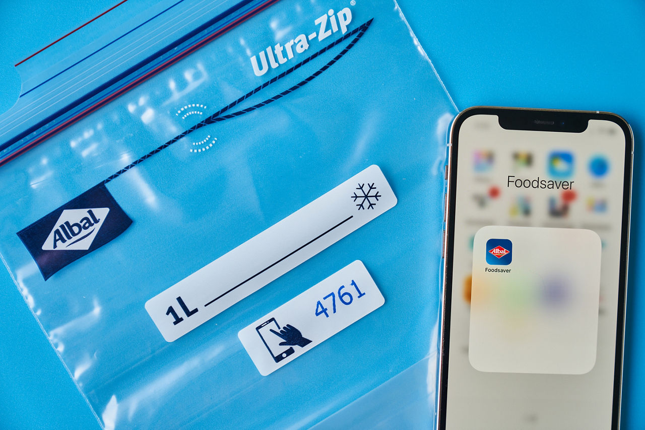 Smartphone sur sac de congélation avec code de fraîcheur sur fond bleu