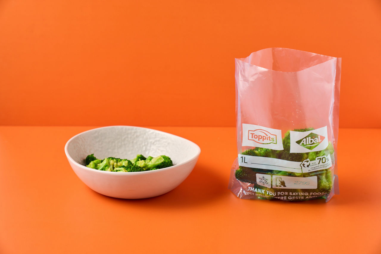                                Schale mit Brokkoli und ein geöffneter Toppits/Albal Gefrierbeutel mit Brokkoli auf orangem Hintergrund
