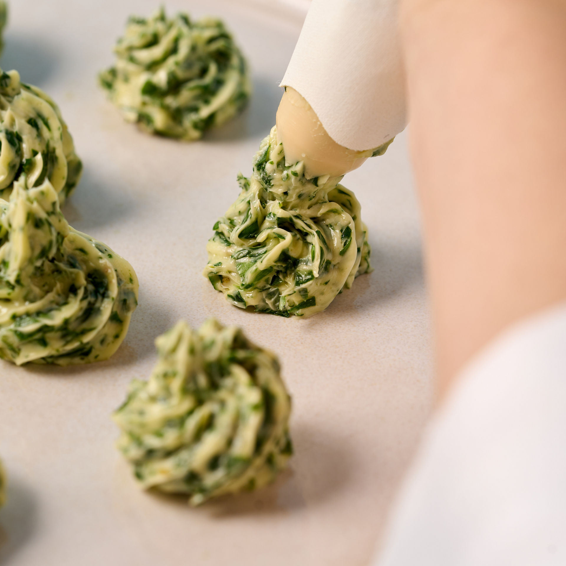 Hånd sprøjter kryddersmør på en tallerken med en Toppits® sprøjtepose